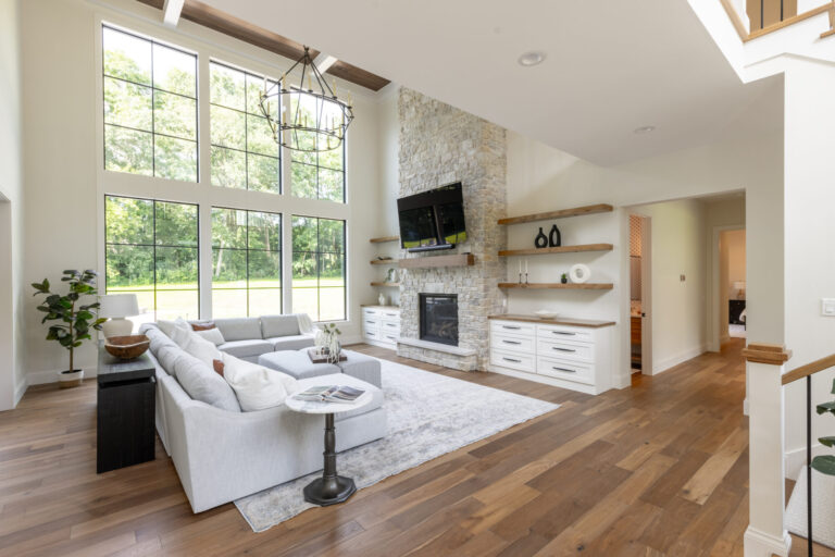 living room with floor to ceiling windows hardwood flooring fireplace with flat screen tv and white couch