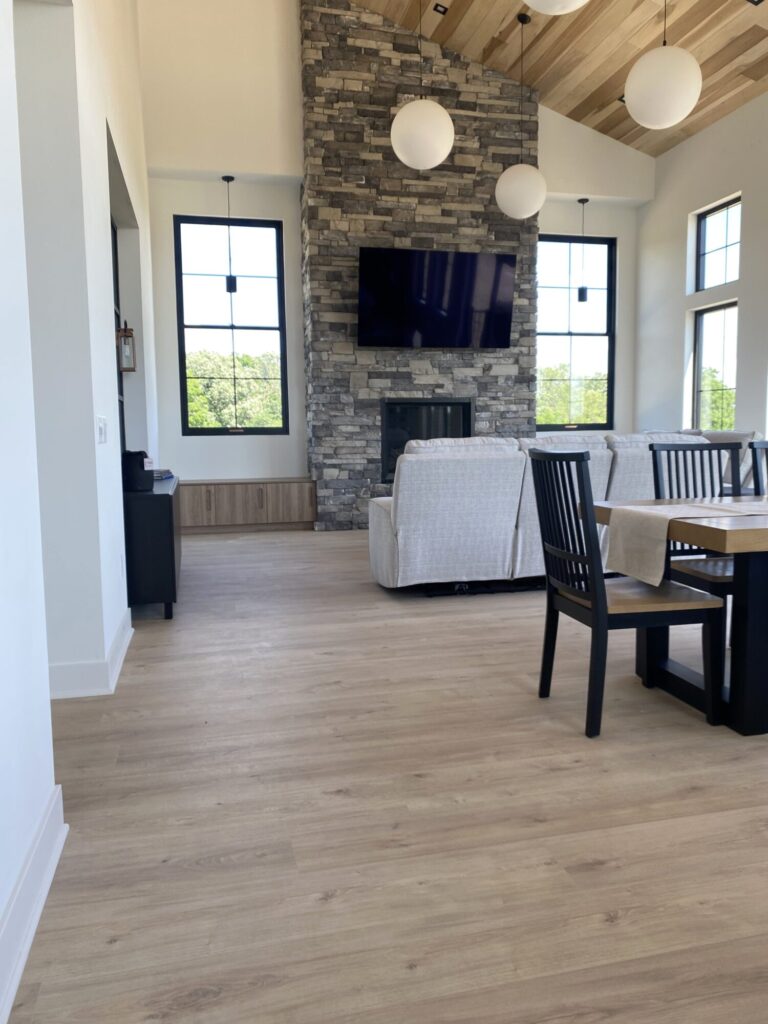 living room view of fireplace stone tile surround installed floor to ceiling and wood look laminate floor