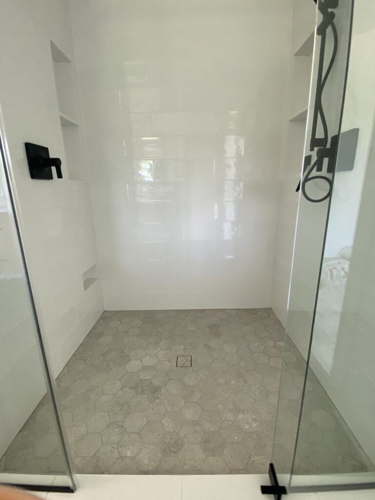 walk in shower with beige tile floor and cream tile walls