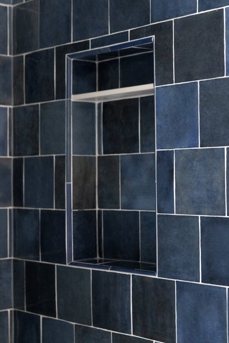 blue textured tile like zellige on a shower wall with a small shelf niche