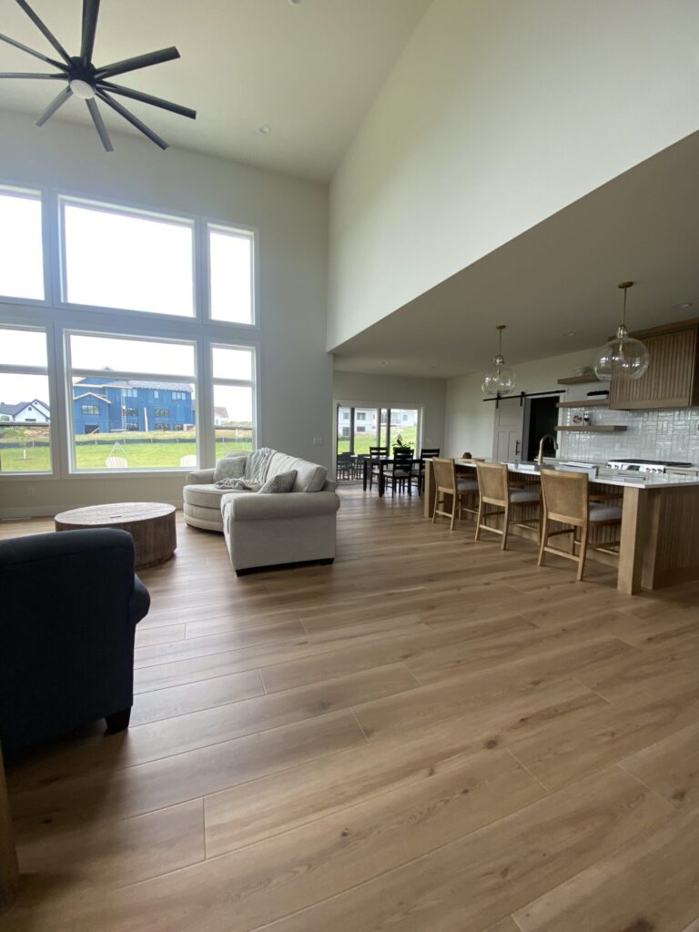 hardwood flooring in a great room with a kitchen island over size picture window and a couch