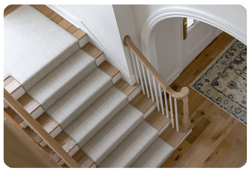 wool carpeting stair runner with ivory and grey stripe pattern wood stairs and white riser 