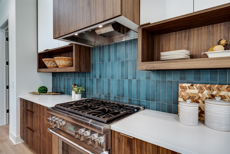 close up of green blue tile kitchen backsplash with white and wood cabinets