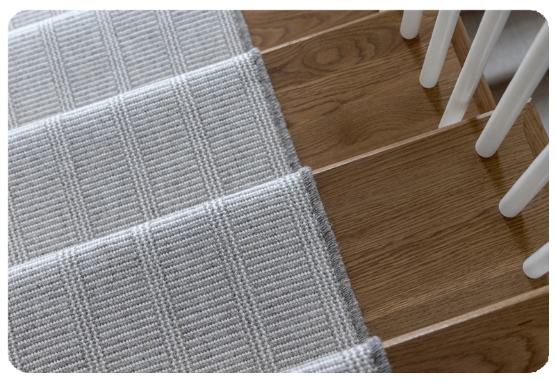 close up of wool carpet stair runner with grey and ivory stripe pattern and serged border