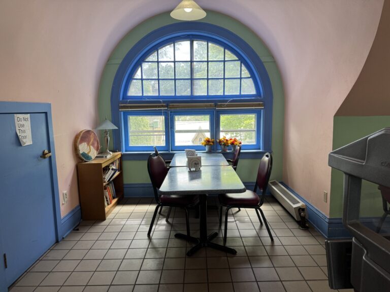 restaurant table seating four centered on a large window with an arch painted in green and blue