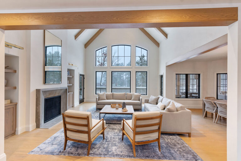 living room with hardwood flooring area rug, chairs, couches and wall of windows
