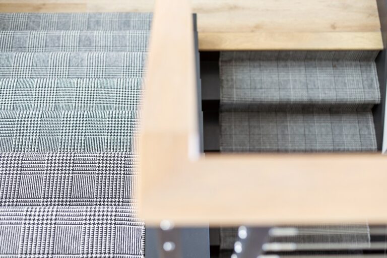 black and white plaid carpet with hardwood railing and landing