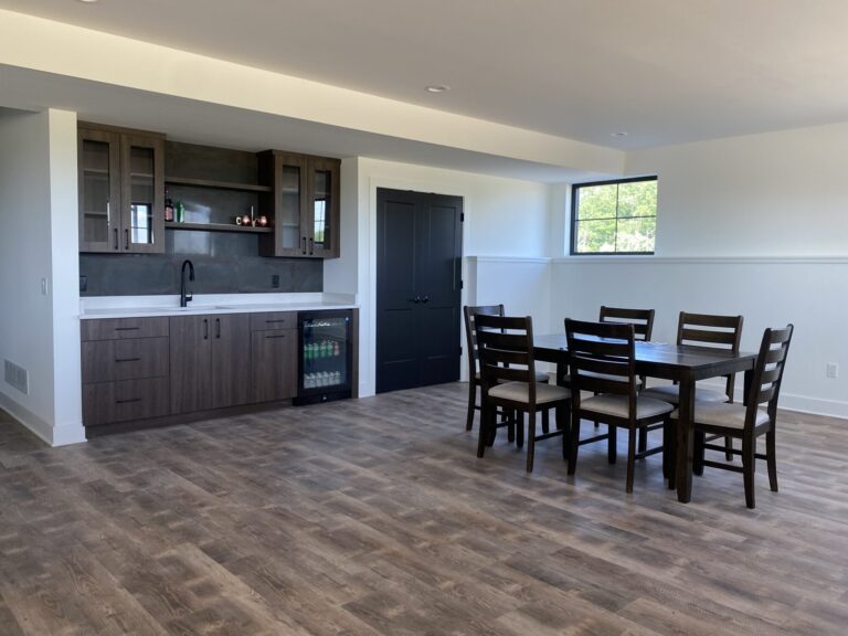 dark brown and white lower level bar area with dark wood look luxury vinyl tile and built in cabinets