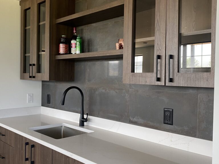 close up of built in cabinet bar with sink and slate grey tile backsplash