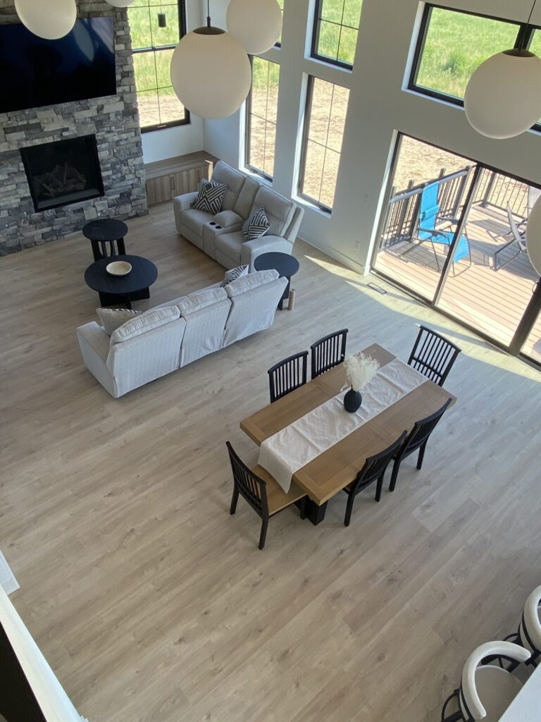view of living room from above dining room table couch and floor to ceiling windows with globe light fixtures