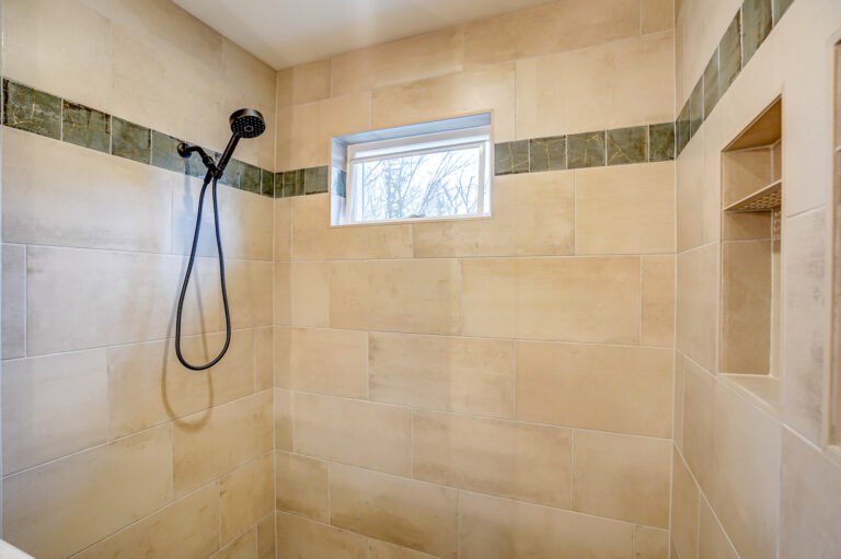 walk in shower with niche beige tile with green tile detail