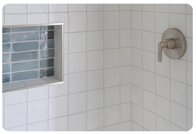 white tile shower with teal tile niche
