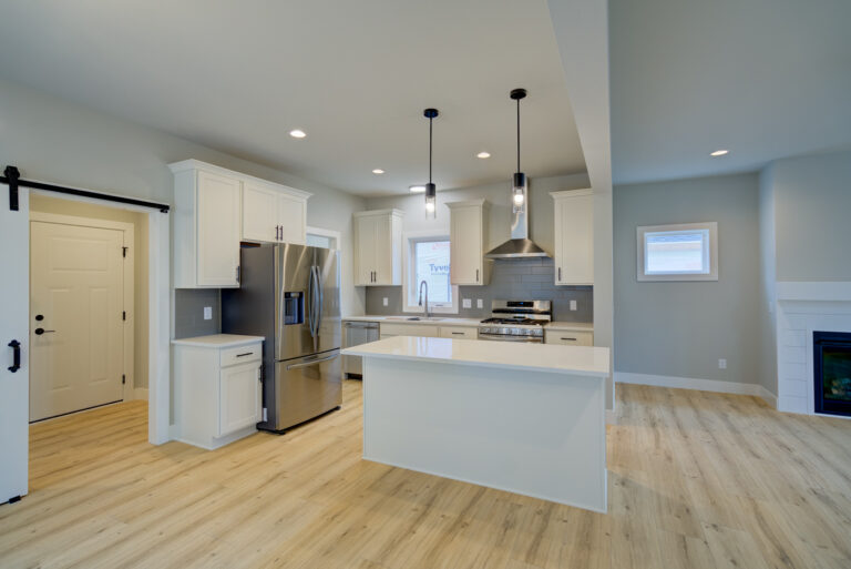view of kitchen with wood look luxury vinyl plank flooring white cabinets and grey tile backsplash