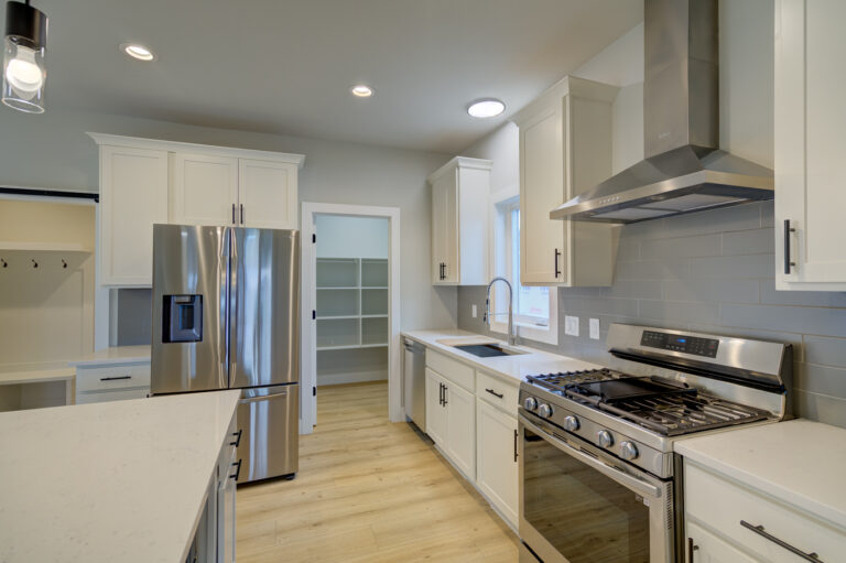 view of kitchen with wood look luxury vinyl plank flooring white cabinets and grey tile backsplash