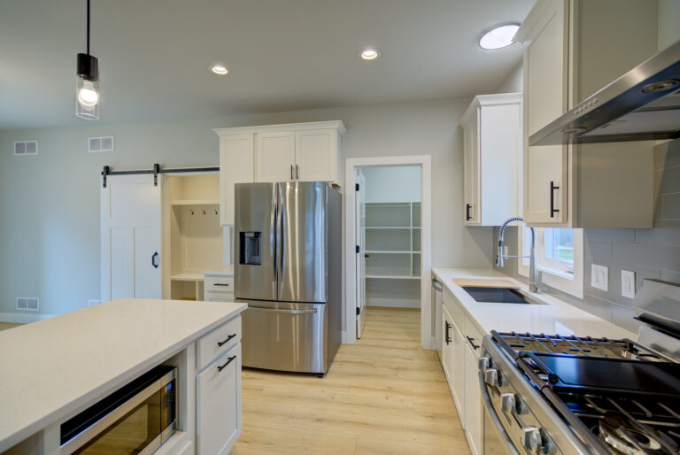 view of kitchen with wood look luxury vinyl plank flooring white cabinets and grey tile backsplash