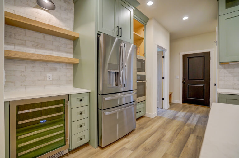 wood look luxury vinyl plank flooring with stainless appliances and white tile backsplashes