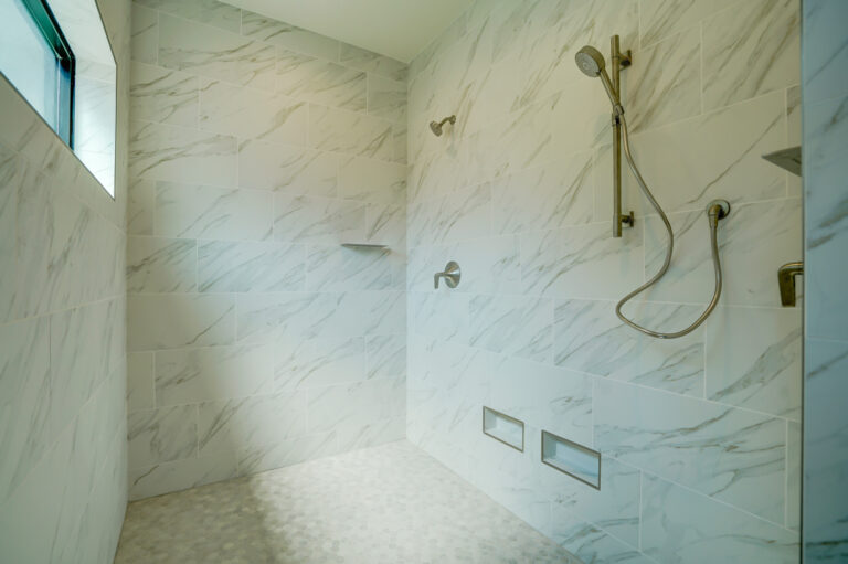 white marble tile shower with a window and small niche shelves