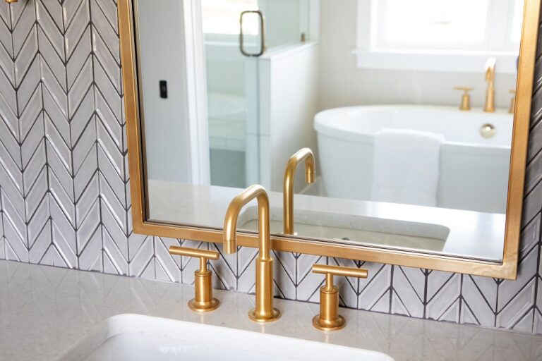 chevron pattern grey wall tile with brass frame mirror
