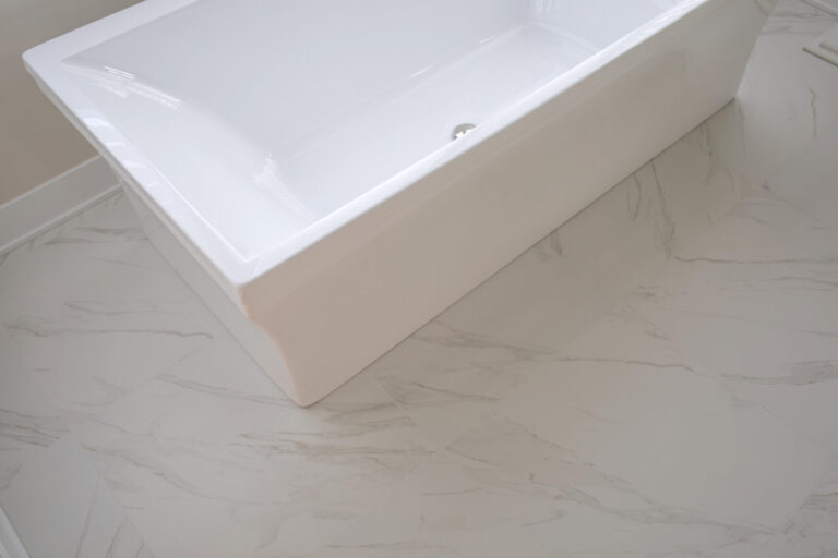 white marble tile floor under white free standing tub