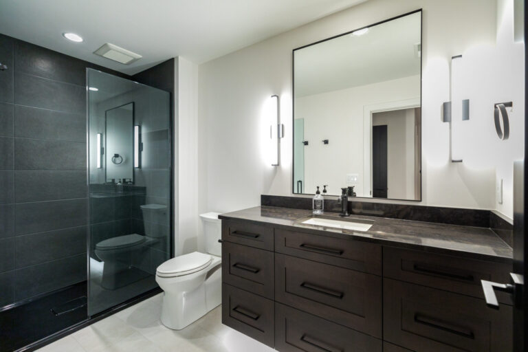 dark wood vanity with mirror and dark grey tile walk in shower