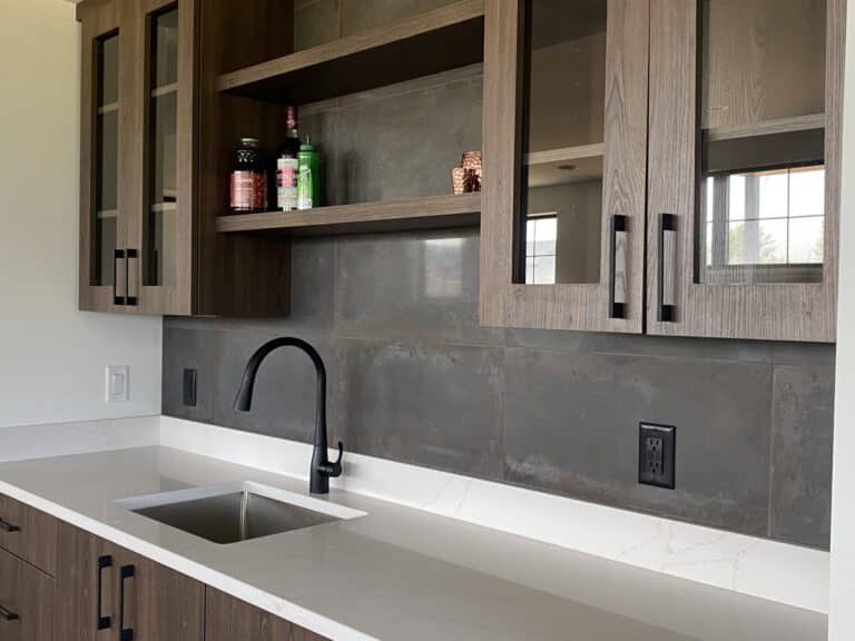 close up of built in cabinet bar with sink and slate grey tile backsplash