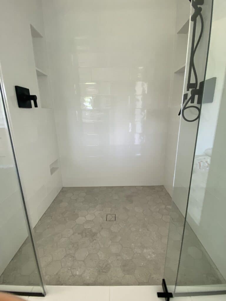 walk in shower with beige tile floor and cream tile walls