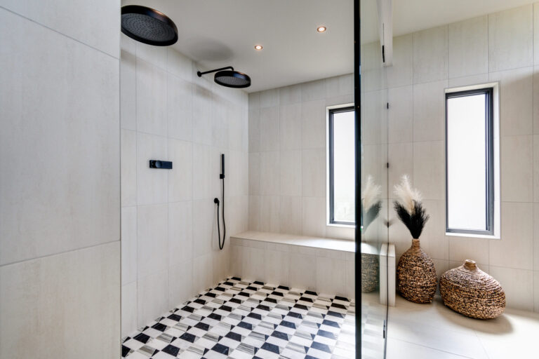 black and white tile floor in curbless shower half glass wall white tile walls black plumbing fixtures