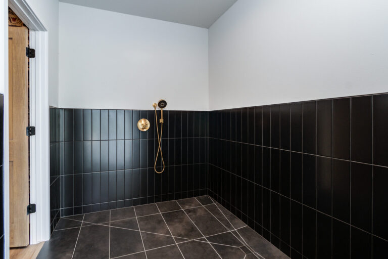 dog shower with half white tile half black tile wall and brown marble floor