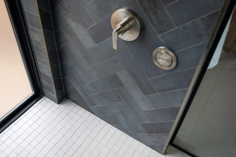 close up of shower floor with small square white tile and herringbone pattern grey tile