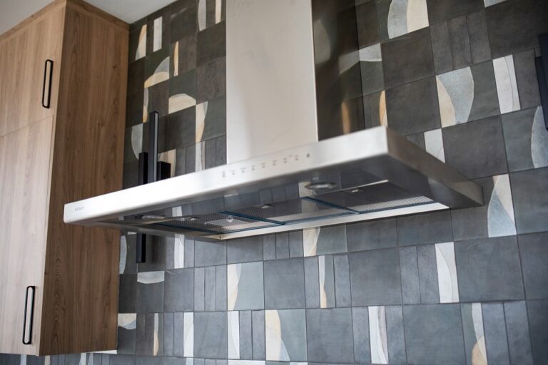 kitchen backsplash with grey tile that has alternating designs installed counter top to ceiling wood cabinets