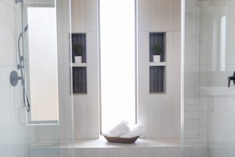 walk in white tile shower on walls and flooring two built in shelves and benches, one window