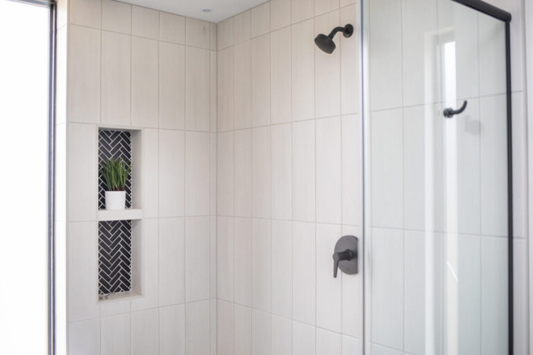 view of shower wall white tile wall and one built in shelf niche