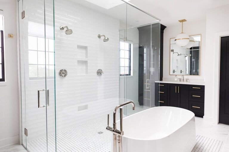 white tile bathroom with free standing tub and glass enclosed shower