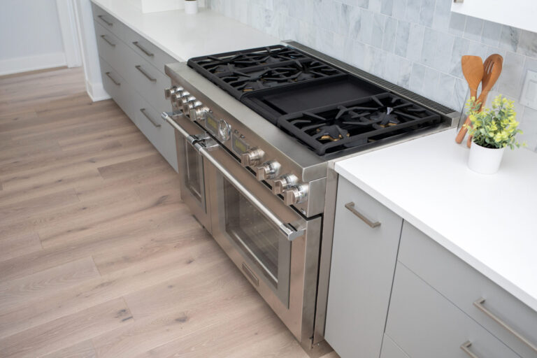 view of kitchen floor hardwood stainless steel gas stove white cabinets and marble tile backsplash