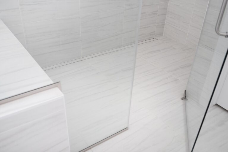 white marble tile walk in shower with built in bench and glass enclosure