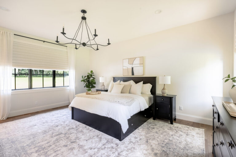 bedroom with large area rug and hardwood flooring queen size bed and black chandelier
