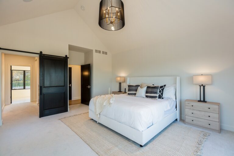 bedroom with wall to wall light grey carpet and area rug under a queen bed with white wall paint