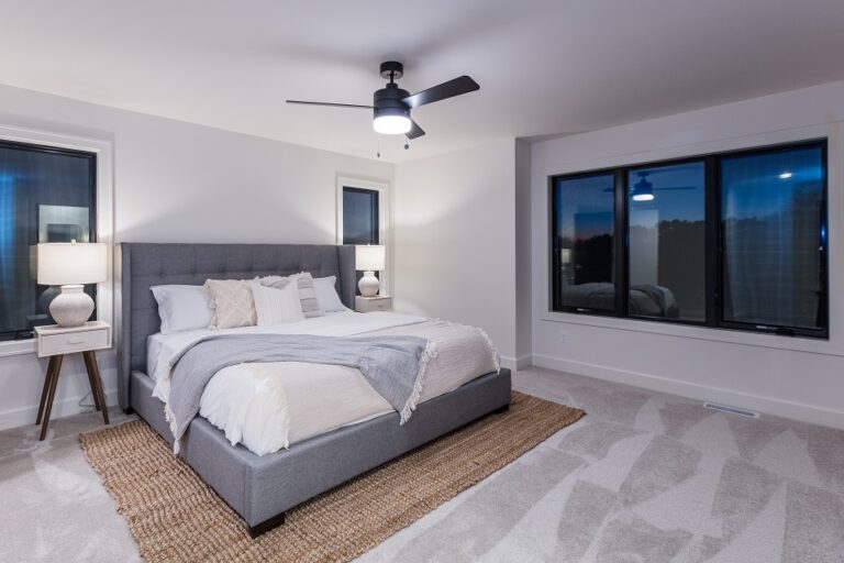wall to wall grey carpeting in a bedroom with queen size bed and area rug under