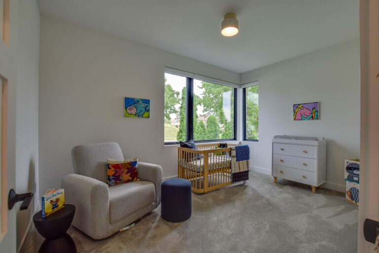 nursery bedroom with wall to wall carpeting crib and soft chair