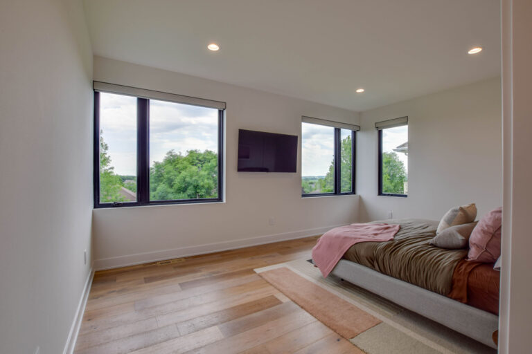 hardwood flooring in a bedroom with a queen size bed and white paint on the walls