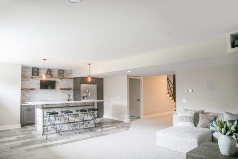 lower level rec room wall to wall grey carpeting and grey luxury vinyl plank floor under the bar with four stools