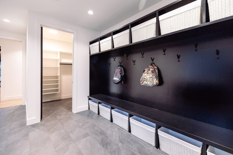 grey tile floor in mudroom with built in coat hooks and storage bins