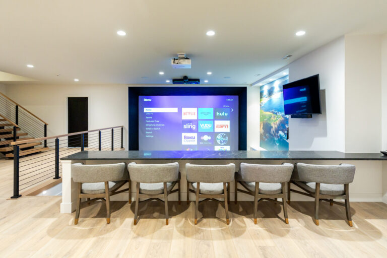 lower level big screen viewing area with countertop and chairs on a luxury vinyl plank wood look floor