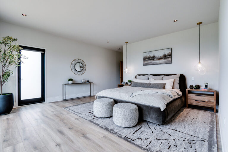 luxury vinyl plank wood look floors in bedroom with area rug under queen size bed and white paint walls