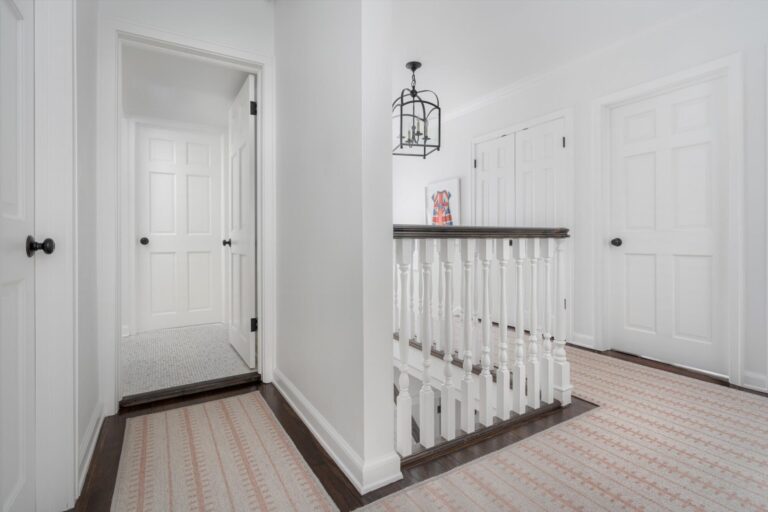 stair runner with red stripe with beige continues from stairs to upstairs hallway