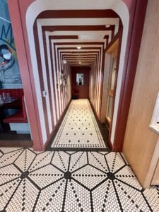 black and white mosaic tile floor installed in a starburst pattern and scattered dot pattern in restaurant hallway