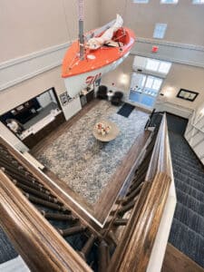 view top of a staircase looking at a lobby with luxury vinyl plank framing a section of floral pattern carpet tile and a large table in the middle
