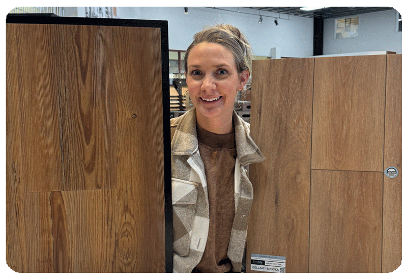 woman holding two sample sizes of luxury vinyl plank flooring standing up next to her