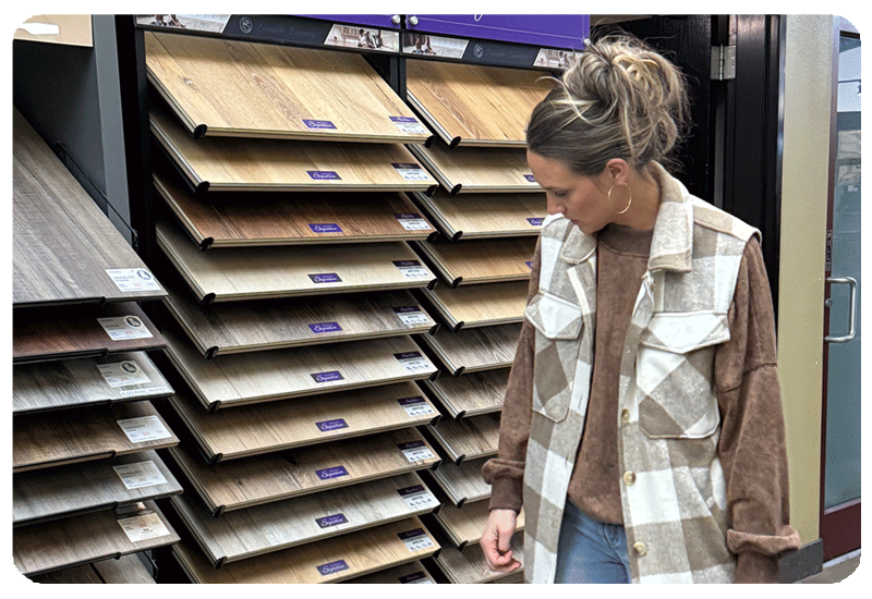 woman looking at a display of wood look luxury vinyl plank flooring sizes