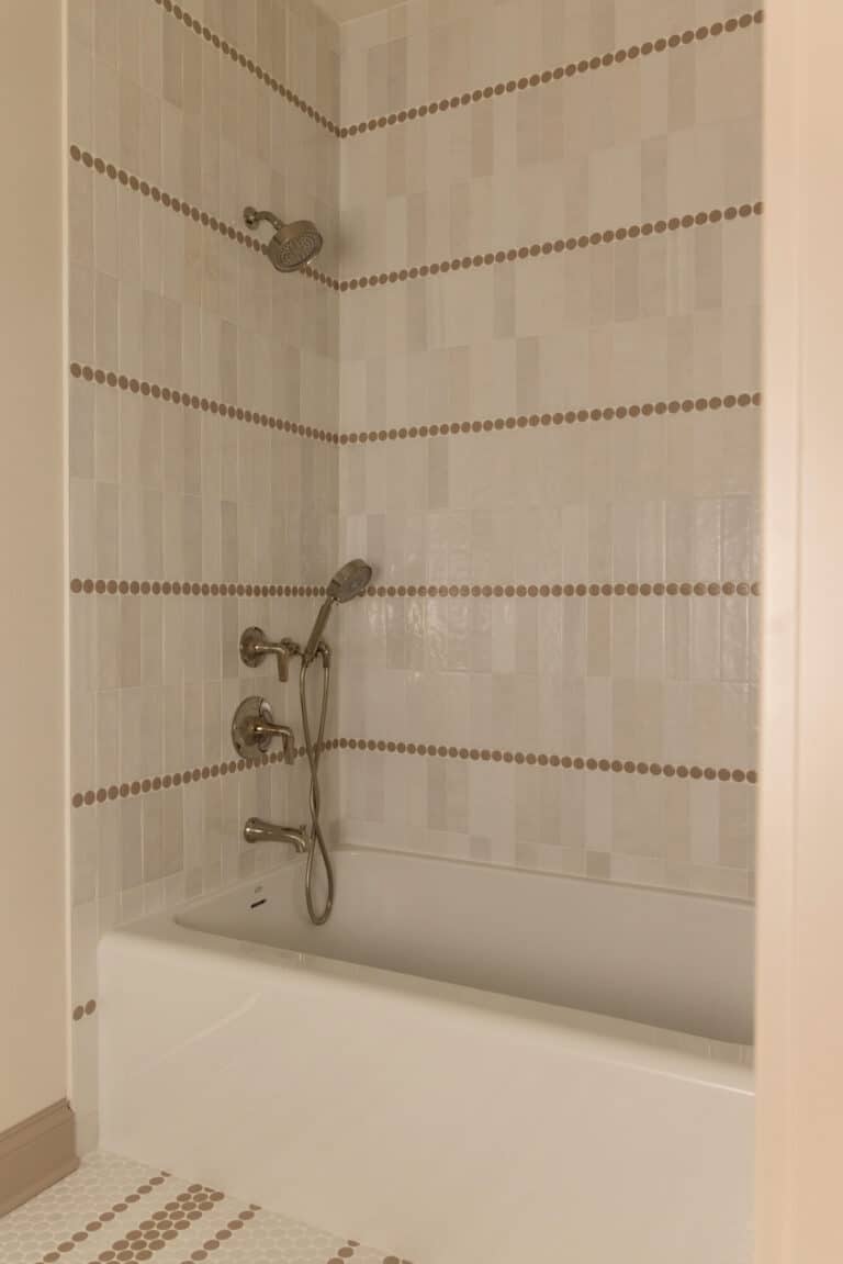 shower tub with tile wall that has cream zellige tile and brown mosaic tile